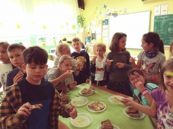 dzieci stoją dookoła stołu i jedz ą różne rodzaje pieczywa z miodem