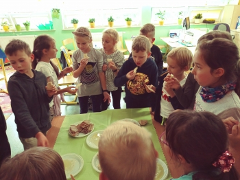 dzieci stoją dookoła stołu i jedz ą różne rodzaje pieczywa z miodem