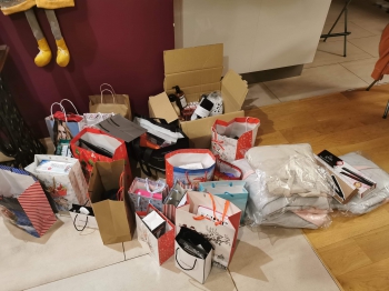 Trzecie zdjęcie przedstawia torebki z prezentami dla podopiecznych z Domu Dziecka ,,Anielsko”. Obok torebek prezentowych są paczki z ubraniami oraz mały sprzęt AGD- 2 prostownice do włosów.